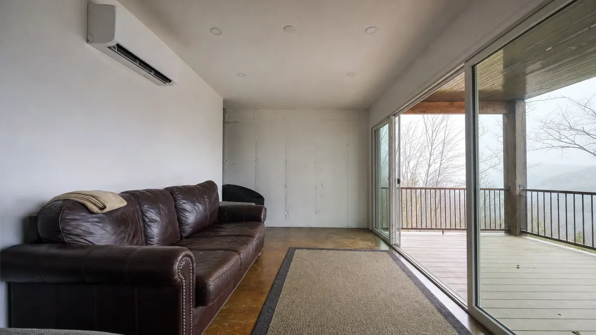 A wall-mounted ductless head conditioning a walk-out terrace level in a North Georgia mountain home, the room the ducted system never reached