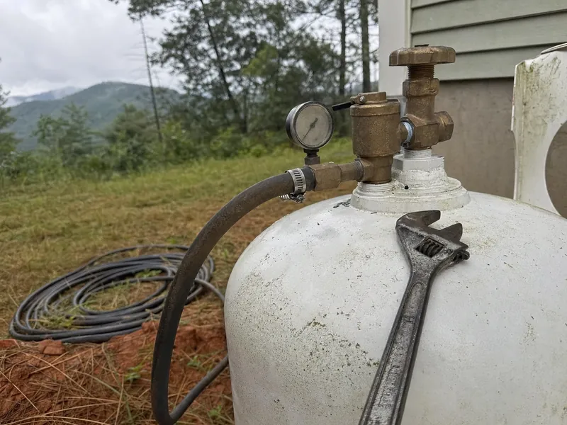 Valve and gauge detail during the purge stage of propane tank decommissioning, the safety-critical step before any cutting or lifting